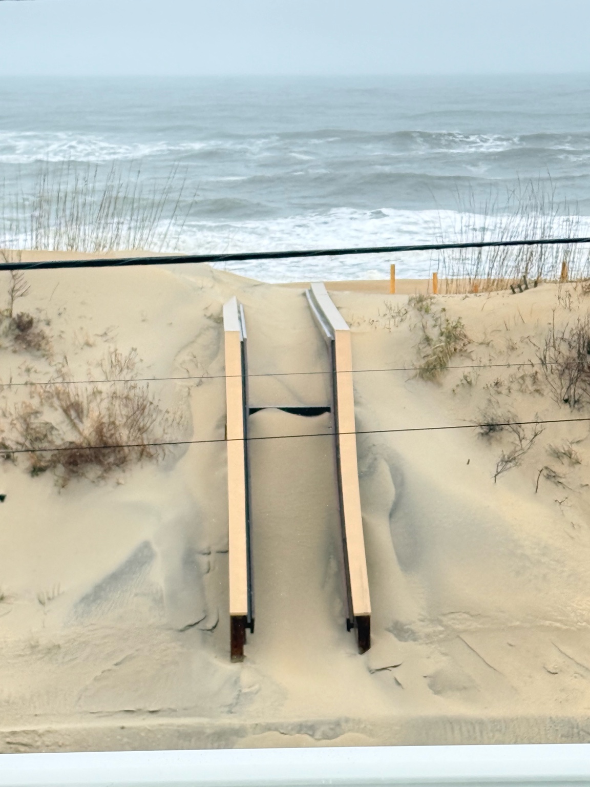 Beach access steps buried in sand after a winter storm in Kitty Hawk
