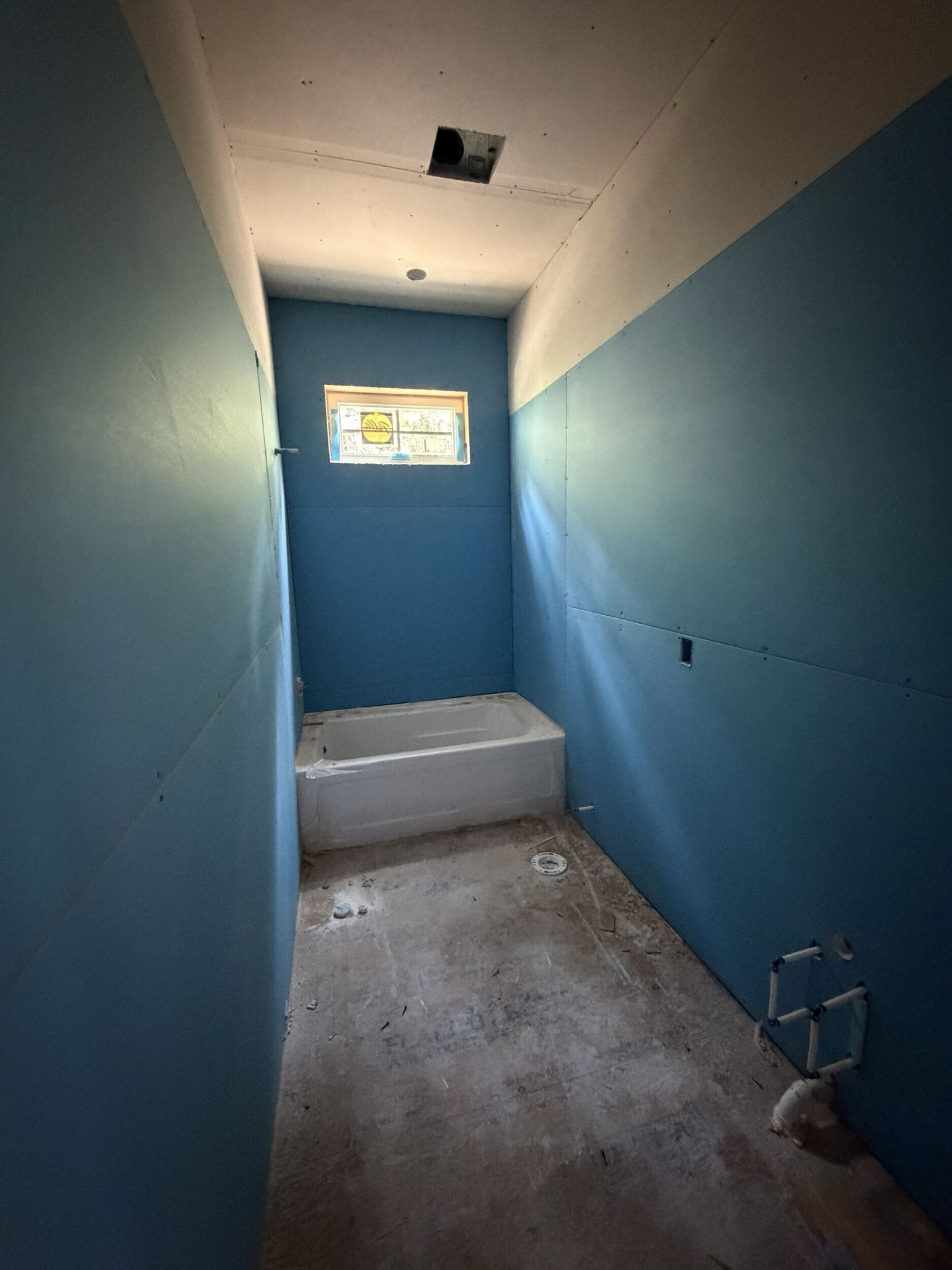 Bathroom under construction with wallboard installed around the tub area