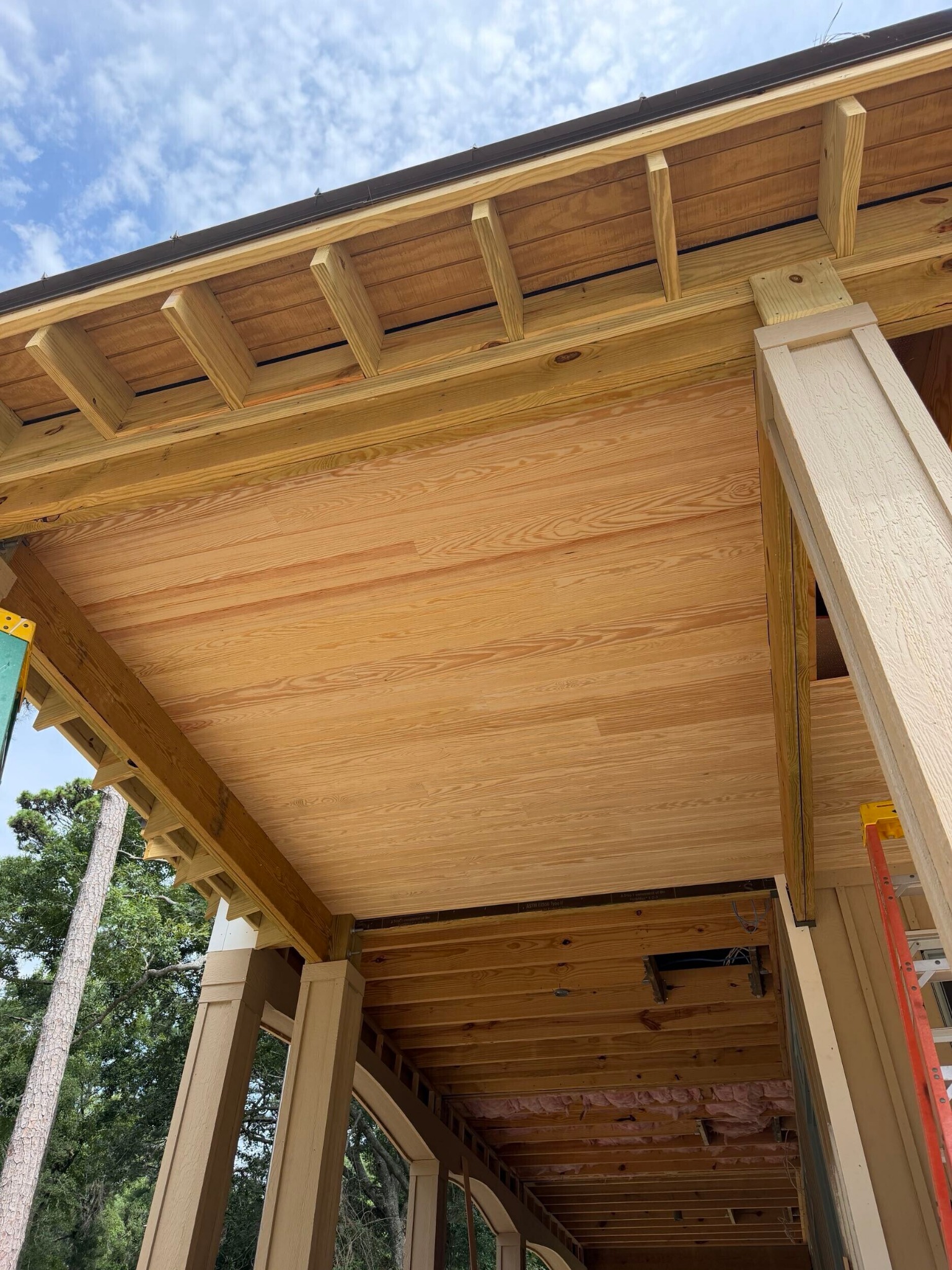 Tongue-and-groove wood porch ceiling being installed on a Southern Shores custom home