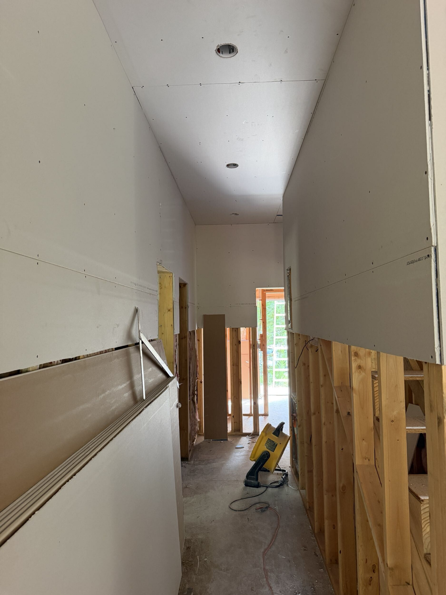 Drywall installation underway in a hallway of a custom home under construction in Southern Shores
