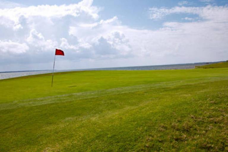 A red flag waves in the wind at the green on a hole at Nags Head Golf Links.